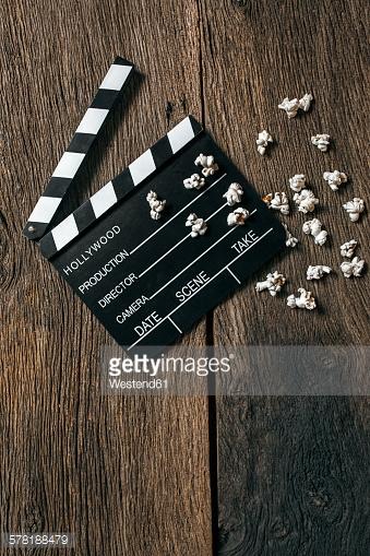 Movie clapper and popcorn on aged wood
