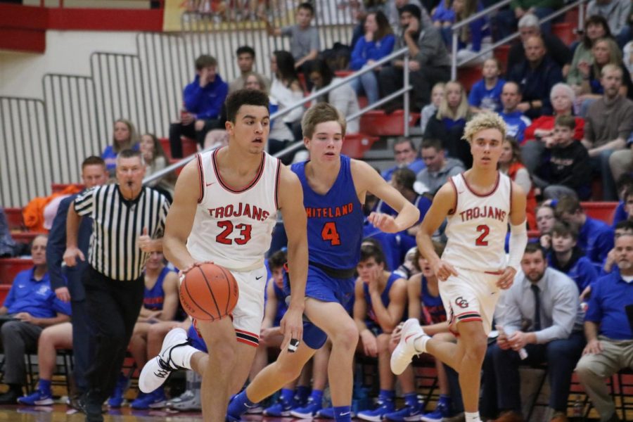 Junior Leyton Mcgovern dribbles the ball down the court during the Trojans second match against Whiteland, followed closely by sophomore Tayven Jackson.