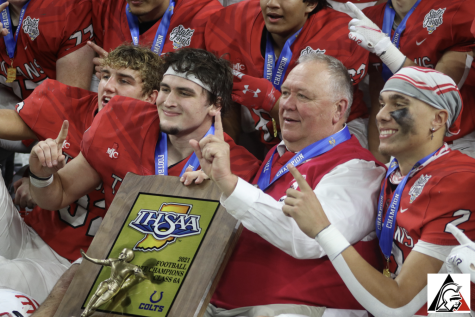 Seniors James Schott, Caden Curry and Tayven Jackson pose with Coach Eric Moore after receiving their state championship medals and trophy. “Its the greatest feeling in the world,” Moore said. “Im so proud of the team and community for their support and really these guys, just staying with it. Thats 28 straight games. Thats history.”