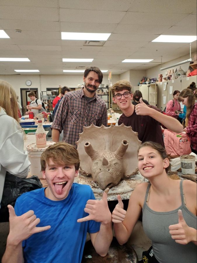 Ceramics teacher Nathan Fry, senior Ben Werner, senior Reece Wilson and senior Hannah Wehrle pose with the in-progress dinosaur head. Photo contributed