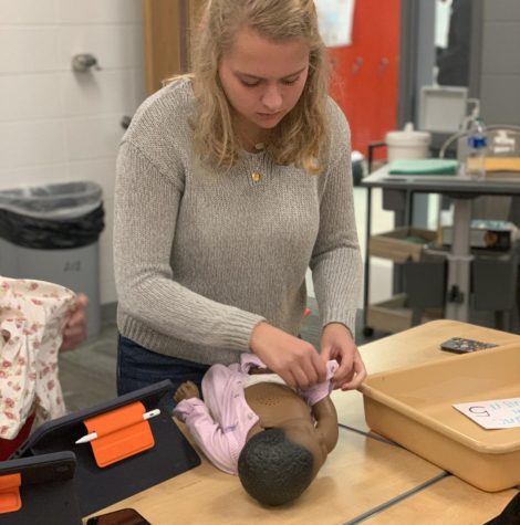 Senior Grace Gagne holds a baby doll during a parenting station activity in Jessica Thomas 7th period Intro to Child Development class.