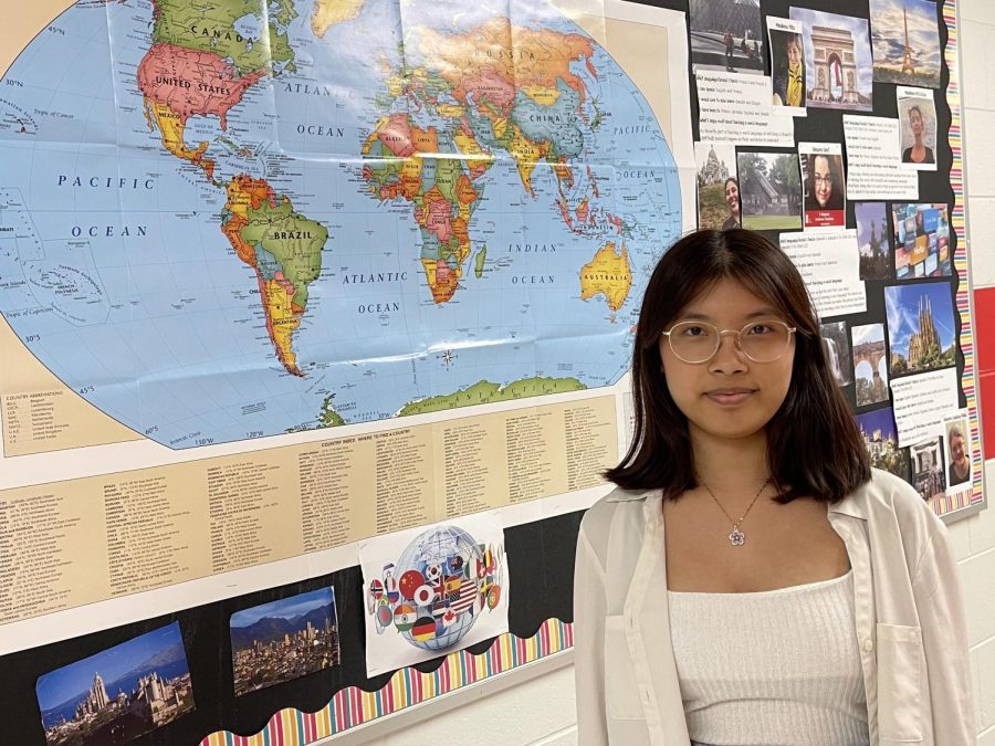 Senior Duh Zathang stands in front of a map of the world. In total, Zathang understands seven languages. 