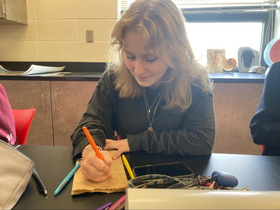 During an Environmental Club meeting, senior Ashley Mitchell decorates a bag. This bag would later be used to collect bottle caps off of plastic bottles to be turned into benches. “I like it because its a good way to get involved in our community and find different ways to get involved in the environment,” Mitchell said. 
