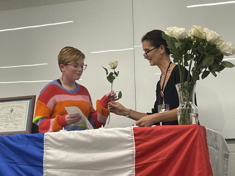 Teacher Madame Severine McClellan inducts sophomore Adeline Moore into French NHS.