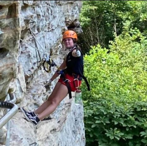 Sophomore Emily Strother gives a thumbs up while rock climbing on Southeast Mountain in Kentucky. Photo contributed