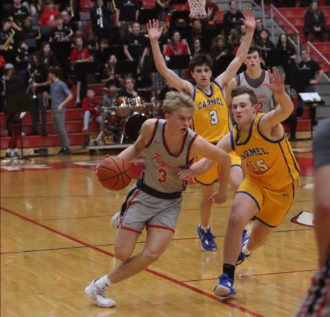 Senior Marcus Ankney drives past Carmel defenders in the Trojans 43-41 win on Jan. 6. Ankney secured the teams win with two free throws in the last second of play.