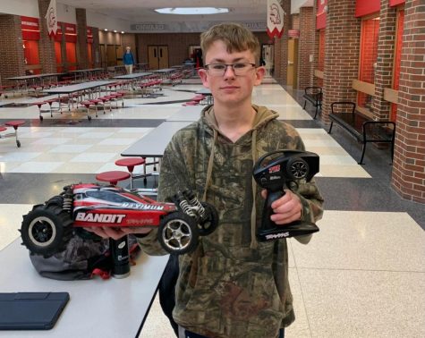 Freshman Ryan June holds up a remote control car and controller.