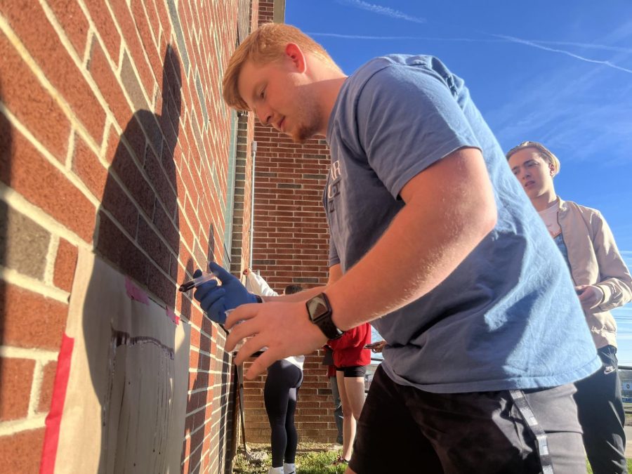 Senior Logan Cravens practices forming blood splatters against a wall on Thursday during Sommer Meyers forensics class.
