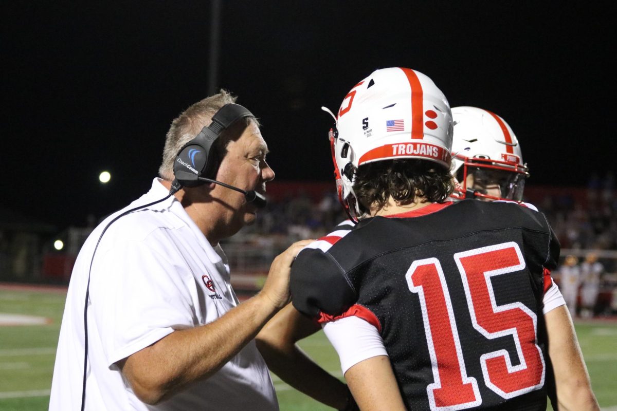 Senior Tyler Cherry and coach Eric Moore discuss on the sidelines during their game against Carmel last year. The Trojans would win the game 31-27.