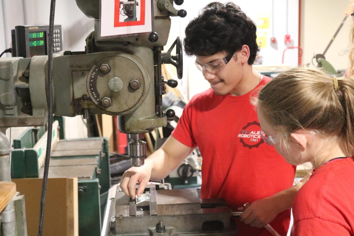 Junior+Nick+Nutley+and+freshman+Kaylee+Holverson+mill+an+aluminum+bracket+during+a+robotics+meeting.+The+mill+is+one+of+many+machines+that+were+able+to+have+their+own+designated+space+in+the+new+expansion.