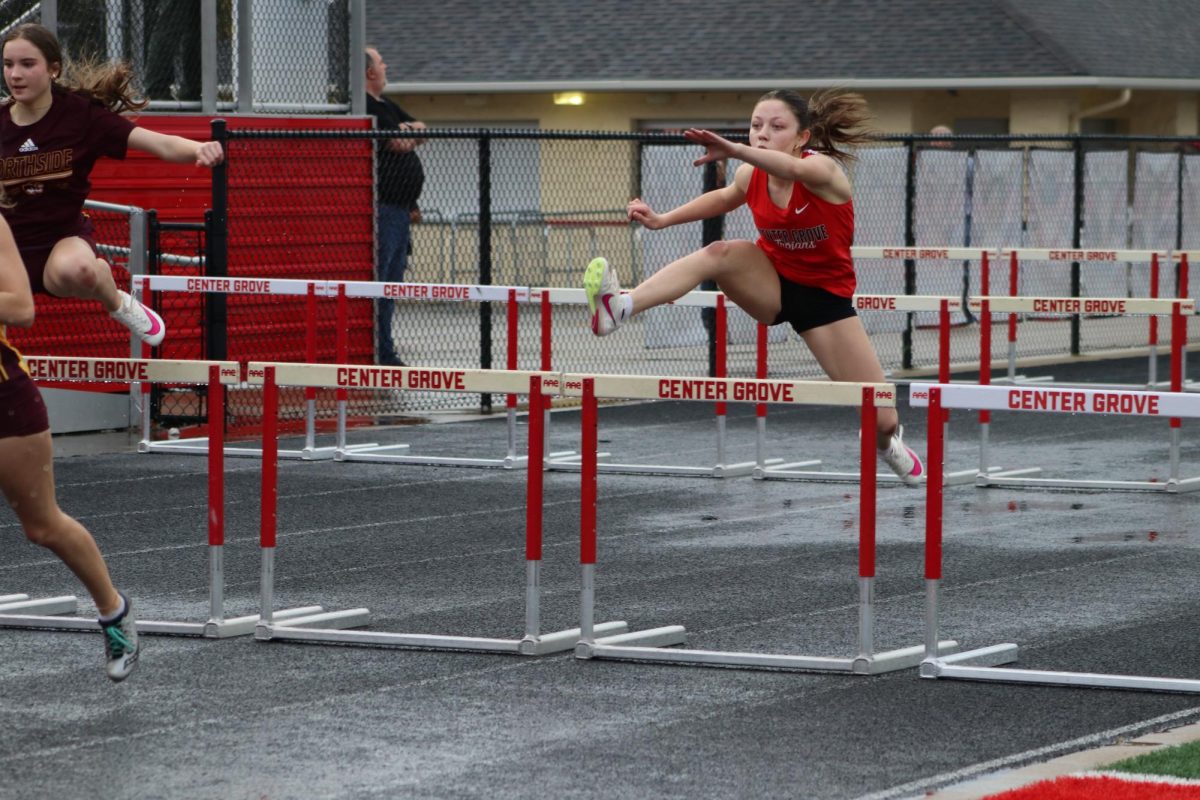 Freshman LillyAnn Payne hurdles her way through a rainy meet at home against Bloomington North. The outdoor meet was originally postponed due to lightning, but later continued through the damp. rainy conditions