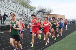Junior Mason Vrshek sticks with the front pack of the 1600m run on the home stretch of the Dennis McNulty Invitational. Vrshek would later pass the pack in his eventual first place finish in the event.