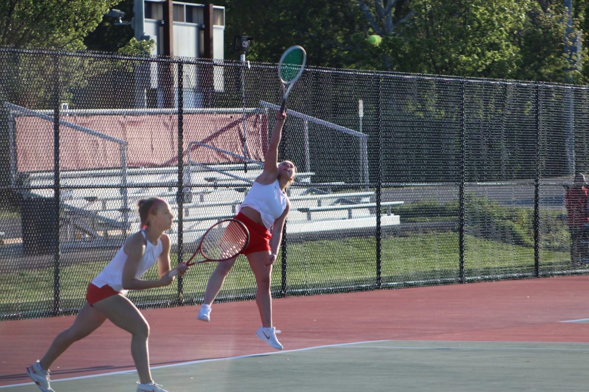 Senior Ava Beecher serves the ball in the game against Columbus North on April 24, while senior Lauren Dick gets ready for the return. The duo would record a decisive victory that would hand the Trojans a 3-2 win against the Bulldogs.