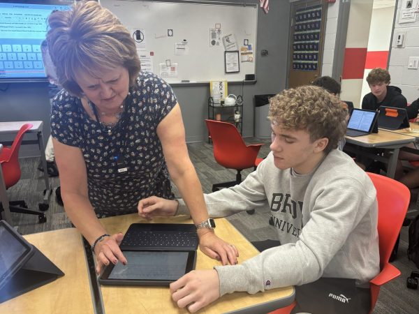 Teacher Debbie Nolan assists senior Silas Stits during the class' coffee shop business activity.