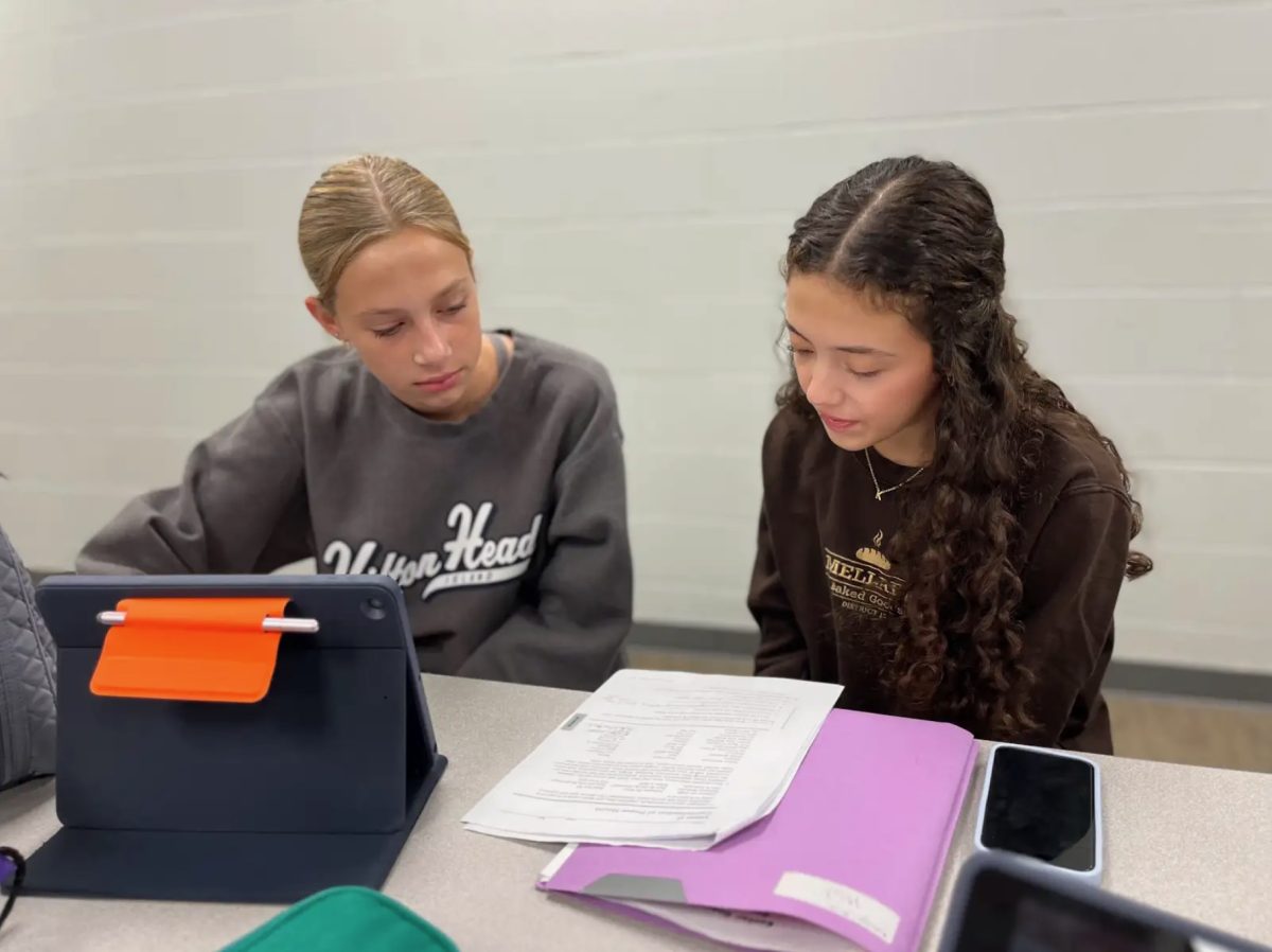 Sophomores Katelyn Ault and Sara McComas work on homework together before school. Many students gather in the morning at the lunch tables in the cafeteria or in the Hall of Excellence to work with friends. “I like to get things done in the morning because then that means I have more time at night to do the things that I want to do,” Ault said. 