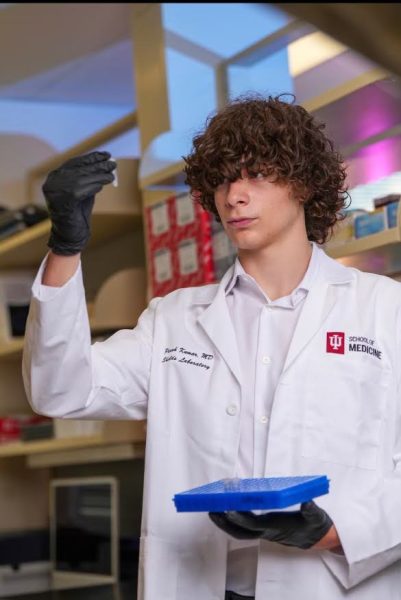 Junior Anthony Cuadros looks into a test tube at Shields Research Lab. Photo contributed.