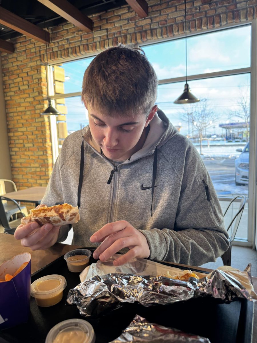 Preparing to dip his new Cheesy Dipping Burrito, senior Gabe McWilliams relaxes at Taco Bell after school on Thursday, the day the new creation was released. “The new burrito was really good because it was extremely cheesy,” McWilliams said.  “I would highly recommend it.”