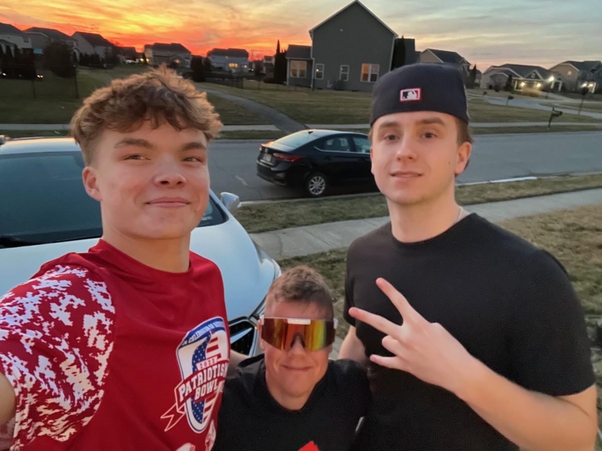 Juniors Vinny Hayse and Ashton Harper pose with a customer in front of a car they detailed.