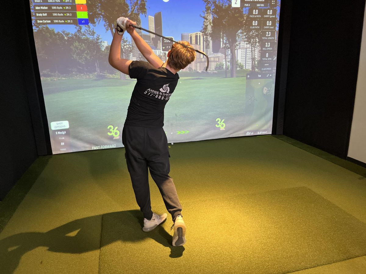 Freshman Tripp Kloboves takes a swing on the new golf simulators. Kloboves and the golf team practice at the new sports facility six times a week and utilizes the new technology and putting green. "It was worth the money and the time," Kloboves said.