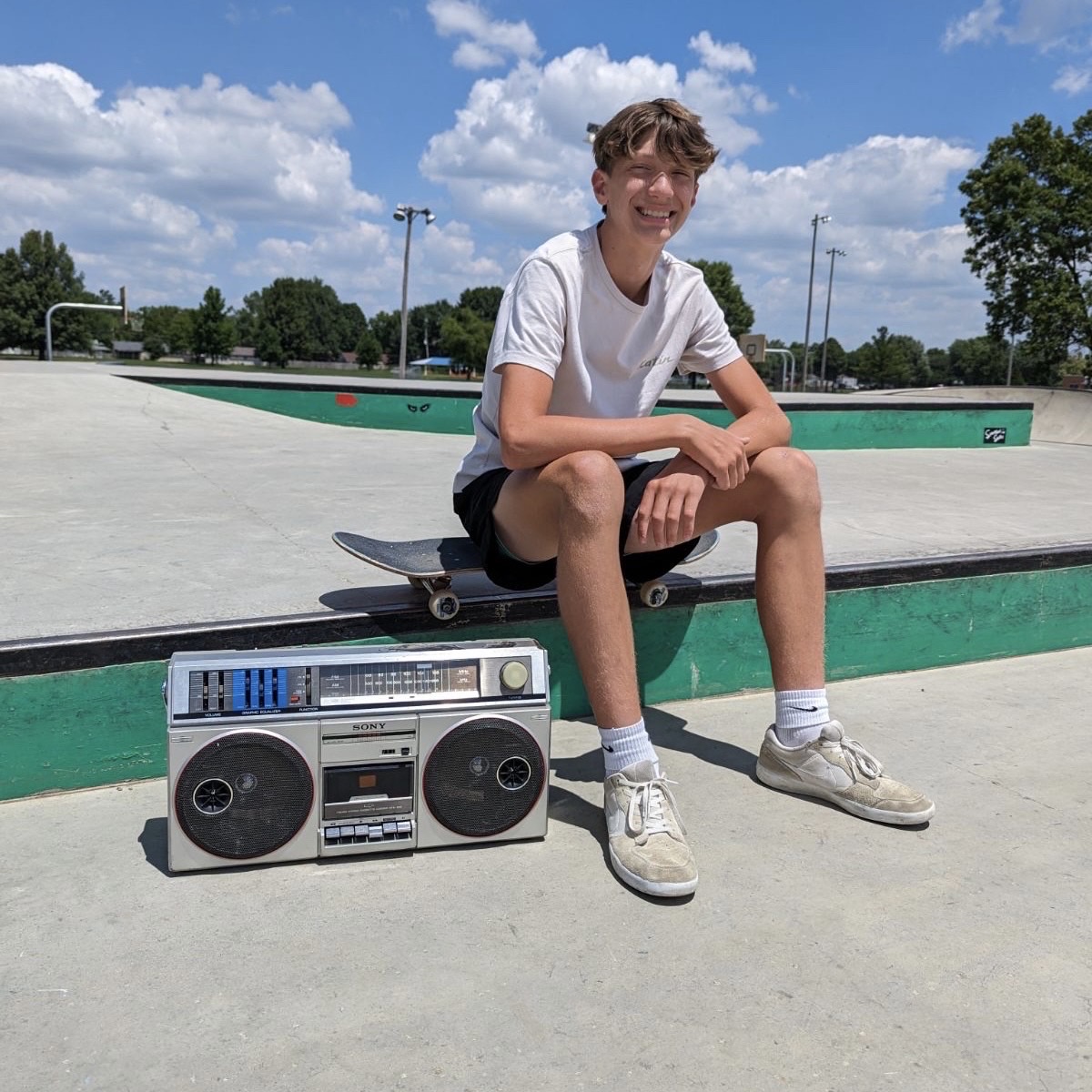 Sophomore Charlie Rolfsen skateboards poses with a speaker and his skateboard.