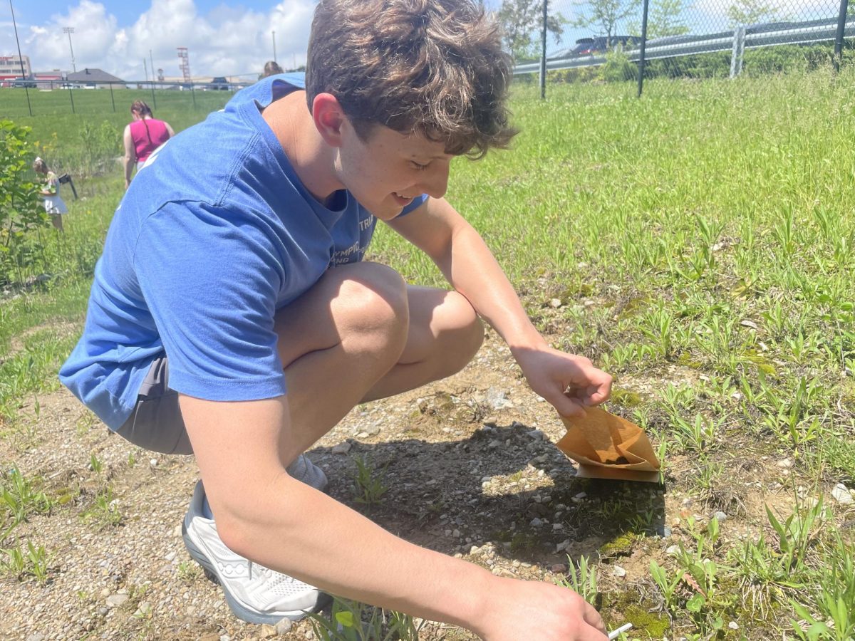 Senior Max Hite collects a moss sample outside for microbiology class. The students collected the samples to observe them under a microscope to see what they can find. "We're collecting and studying moss, lichen, and pond water samples, to wrap up our bacteria and fungi unit, and then we're going to see if we can find tardigrades and other microorganisms," Hite said.