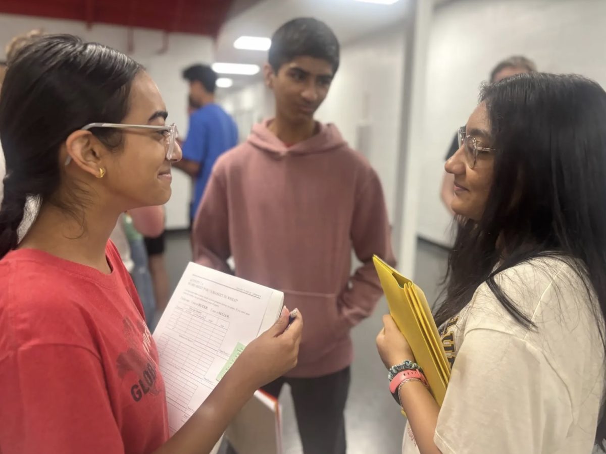 "Senior Sukhmit Jheeta negotiates a trade with classmate senrior Shehreen Musa during John Moore’s sixth period Micoreconomics class. The class used the wheat activity to better understand key concepts like supply, demand and market equilibrium. “This activity helped me engage with my classmates that I normally wouldn’t talk to, while also allowing me to better understand key economic concepts that I will use to further my knowledge in this class,"" Jheeta said."