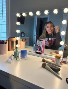 Junior Annabelle Schembra films a TikTok video while doing her makeup