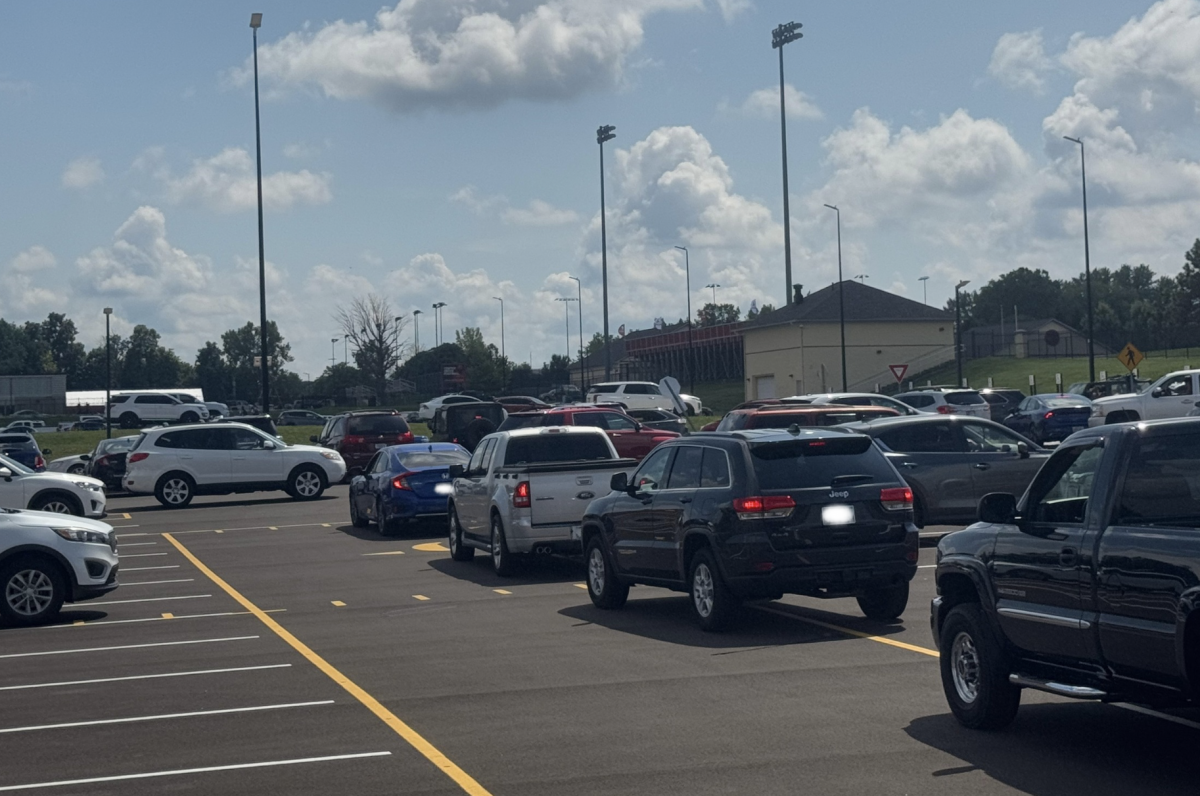 Cars line up behind one another during the end-of-day gridlock in the football parking lot.