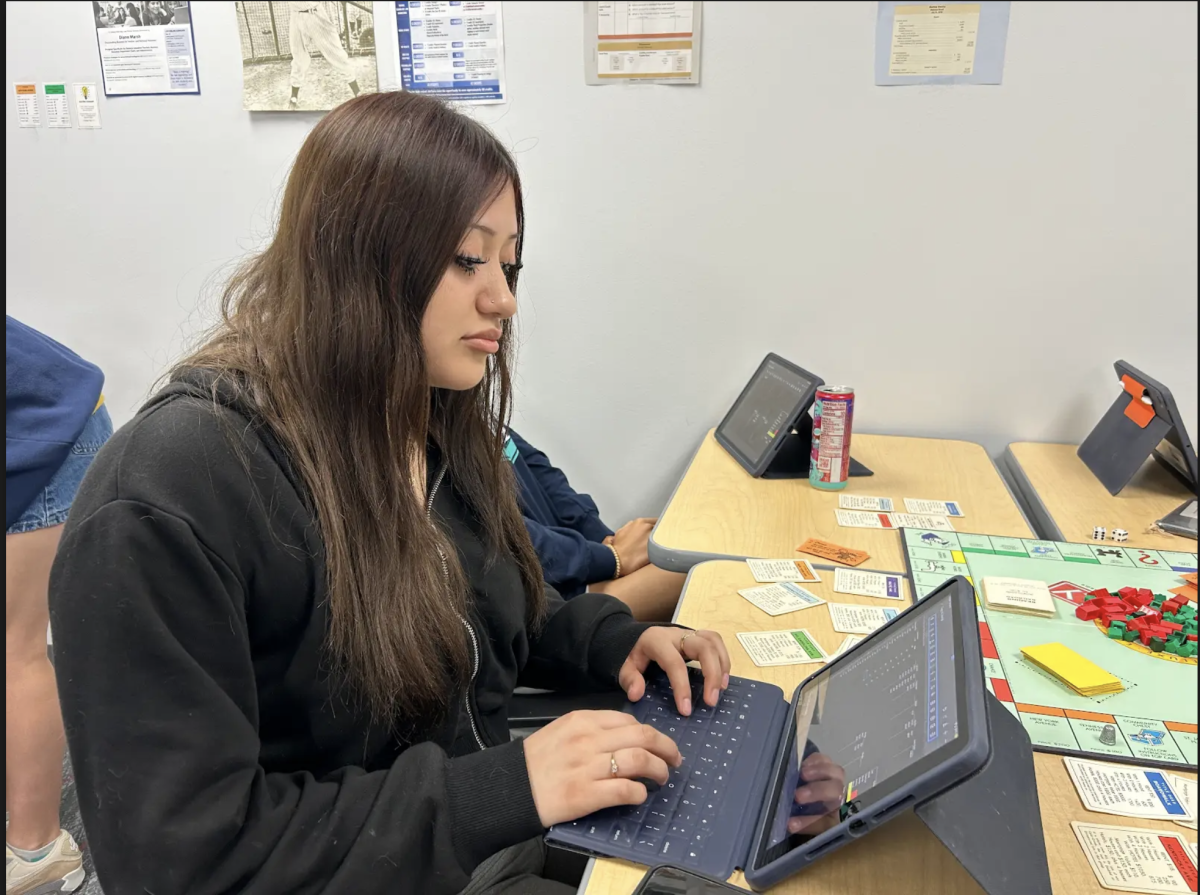 Typing on her iPad, senior Keyla Carmona records her transaction information from her turn in Monopoly. In Accounting Fundamentals, students learned about credits and debits and how to record transactions just like in the real world. “I like playing Monopoly because it allows me to apply what we’ve learned in class to a practical, real-world example," Carmona said. 