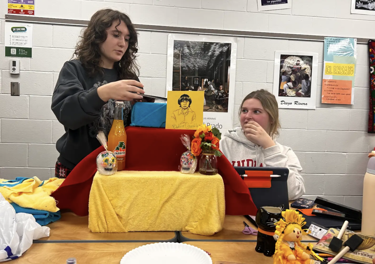 Seniors Jessie Anness and Celia Yurs work together to craft an ofrenda for their Spanish 5 class. The class constructed and dedicated their ofrendas (also known as traditional Spanish altars for Dia de los Muertos) to prominent hispanic artists as part of a project during their art and culture unit. "Our ofrenda celebrates Beatriz Gonzalez, a Colombian artist who painted during the Violence Era," Anness said. "We chose to put her on our ofrenda because we believe her art was incredibly influential as well as reflective of significant political movements of the time."