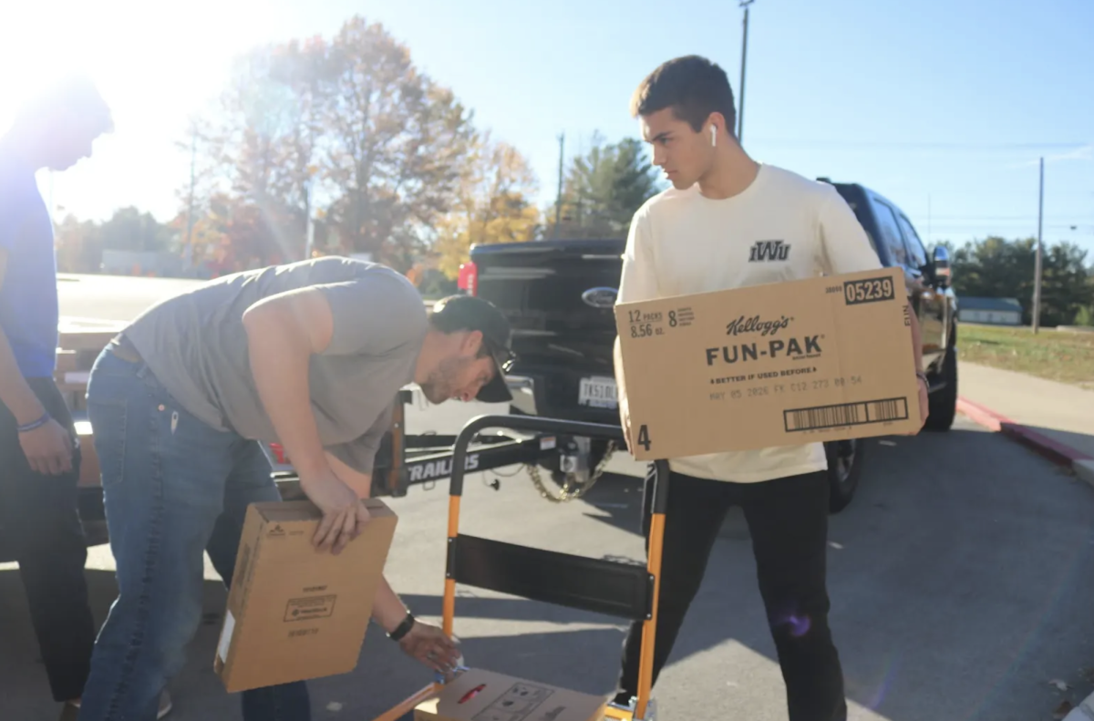 Senior Christian Pitz carries boxes of food during a Blessings in A Backpack event outside the West Gym. On Thursday, Spanish NHS students packed bags of food for families in need in Johnson County. “It was a good opportunity to just do some community service and to get to work with people around you to help those in need," Pitz said.