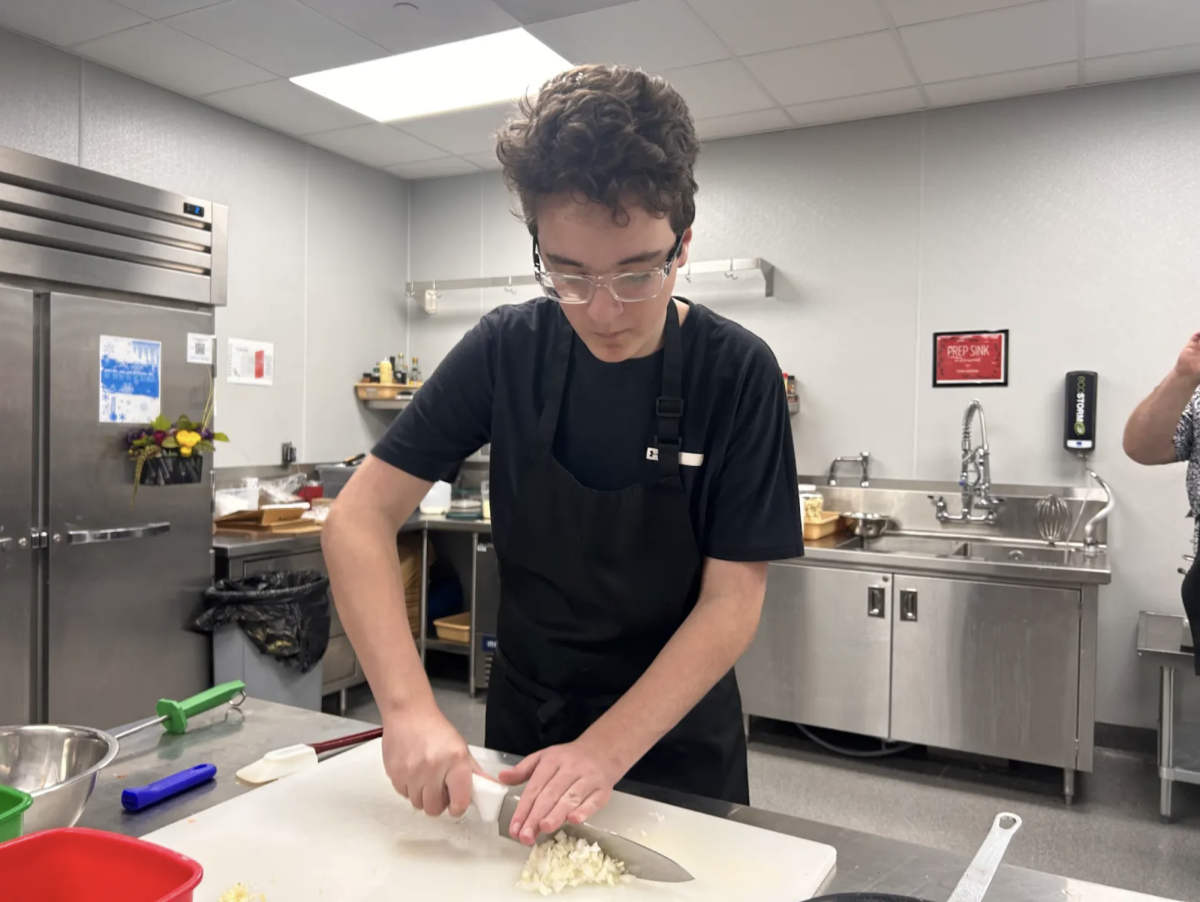 Sophomore Ethan Wix cuts onions for a pasta dish for Culinary. For this dish, students made Chicken Alfredo to help them with their cooking skills that they can use at home or school. “We’re cooking a Chicken Alfredo meal,” Wix said. “This is helpful if I ever have to cook at home because I already know different knife cuts and other skills.”