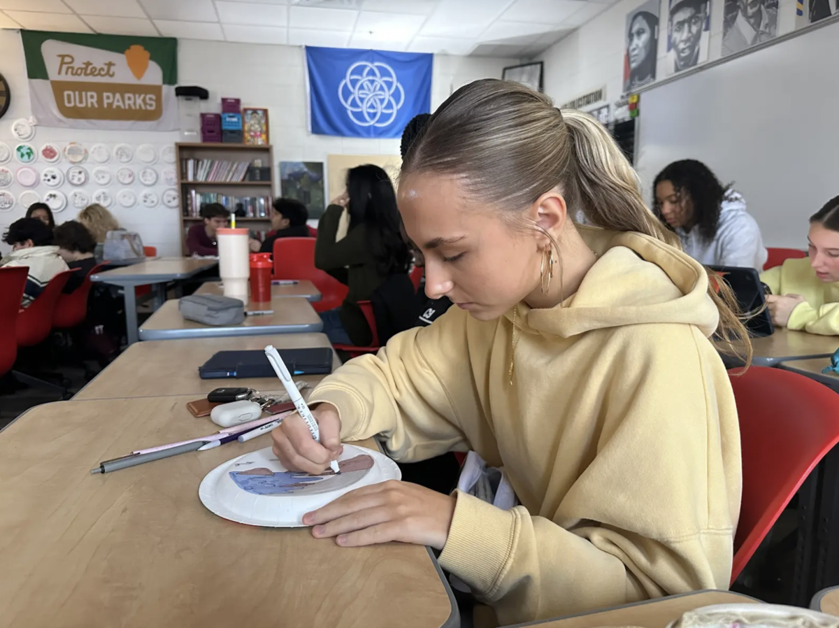 "Senior Ameliah Wasserman works on a personal identity plate during an AP English Literature activity at the start of second semester, drawing different things that represent who she is. This was part two of an activity students completed during the first semester, allowing them to update their plates and reflect on how they may have changed or evolved since the start of the school year. “It was fun to redo it and see how much about me has changed since the beginning of the year,"" Wasserman said.