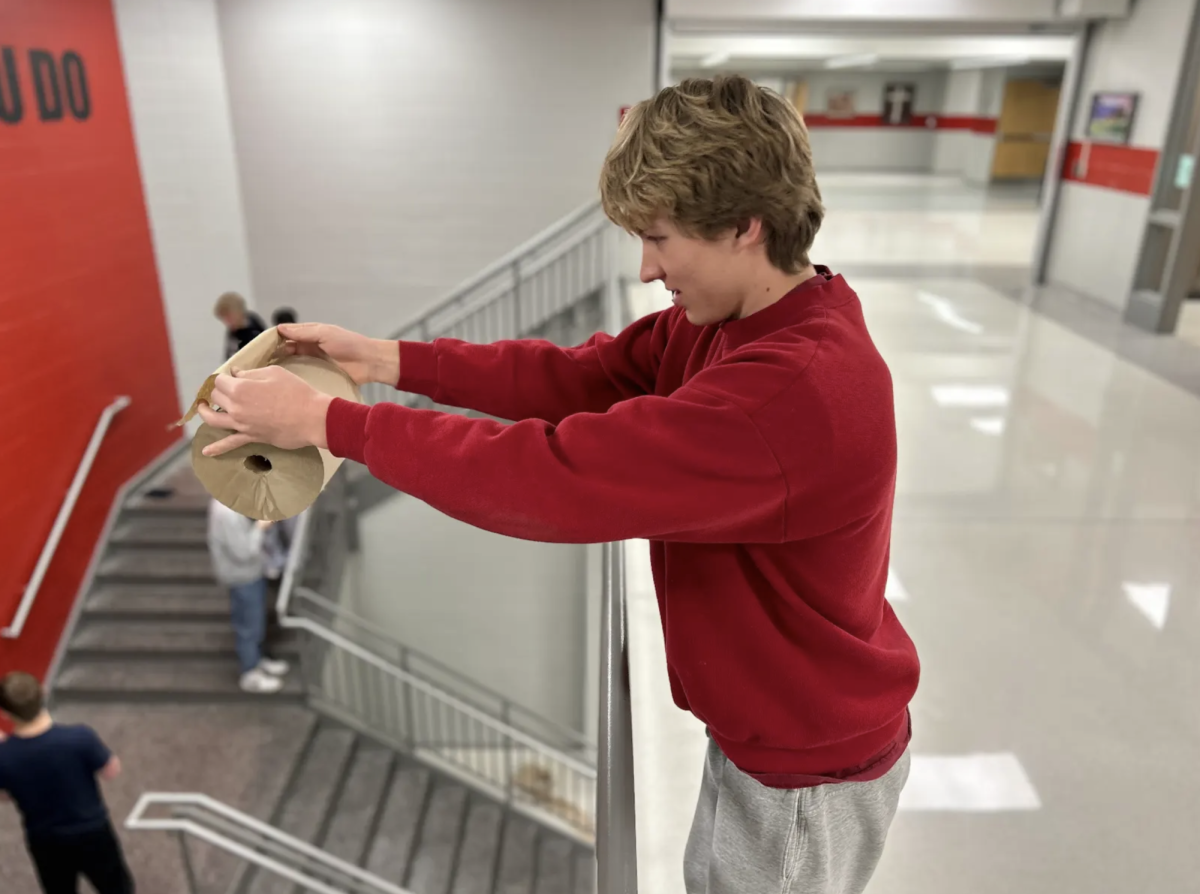 Holding the paper towel across the railing, senior Luke Dagley prepares to release it down the balcony. In Mr. Werner’s AP Physics C Mechanics class, students collected data from dropping the towel roll to learn about torque. “By doing this, I was able to determine the rate at which the roll fell,” Dagley said. “This activity helped me learn physics by showing how tension and torque apply to acceleration.”