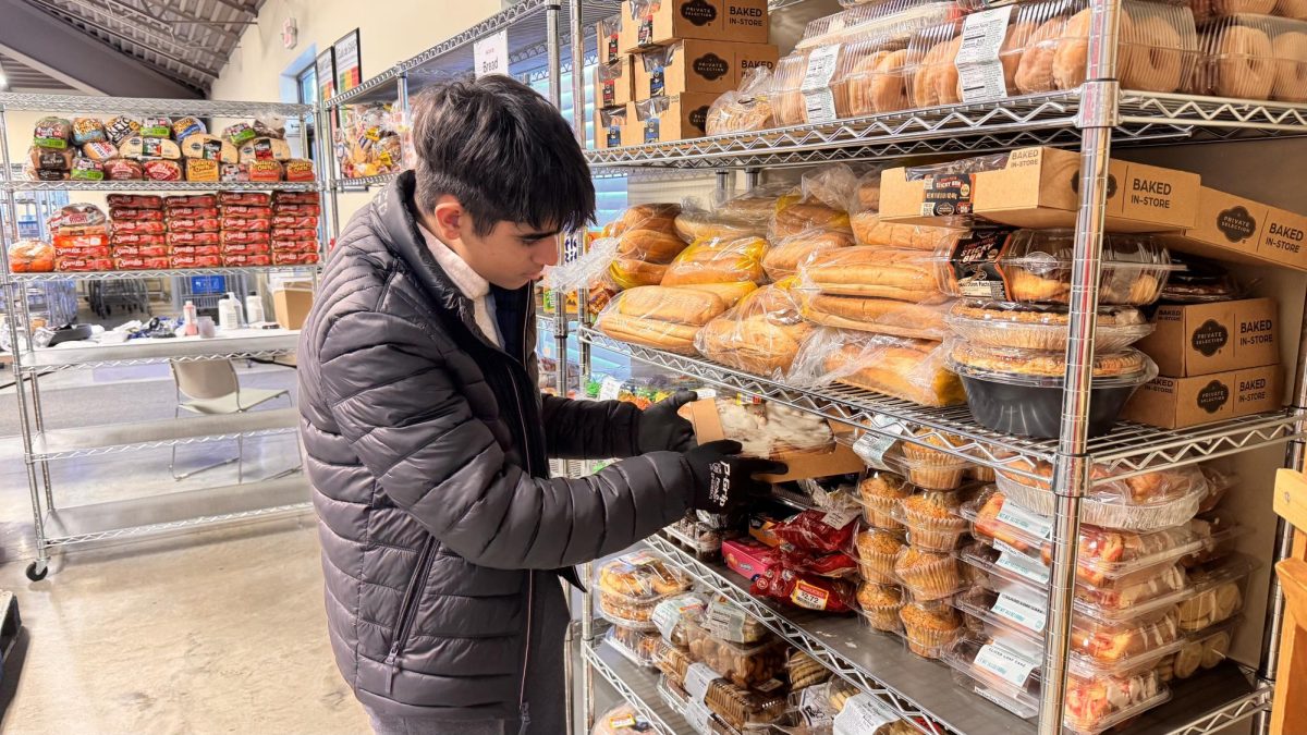 Junior Aryan Kapoor stocks bread at the IMPACT Center. As a result of the snow day, students like Kapoor were left with hours of free time. “I wanted to help have a strong impact on the community while gaining extra volunteer hours for National Honors Society,” Kapoor said.