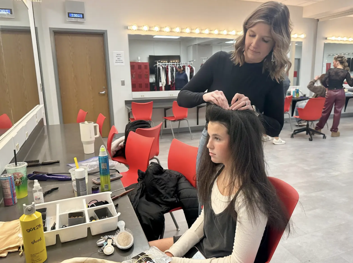 Karoline Langman has her hair done for show choir's pre-contest show by Hannah Sanders, a hair mom. The practice session allowed her to test and finalize her hairstyle before performing on stage. “It helps me feel way more prepared and overall more confident going into the competition," Langman said.