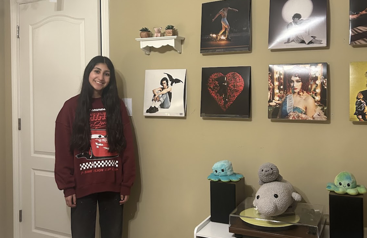 Senior Maddie Guajardo poses in front of her record collection, which features albums from artists such as Conan Gray and Chappell Roan.