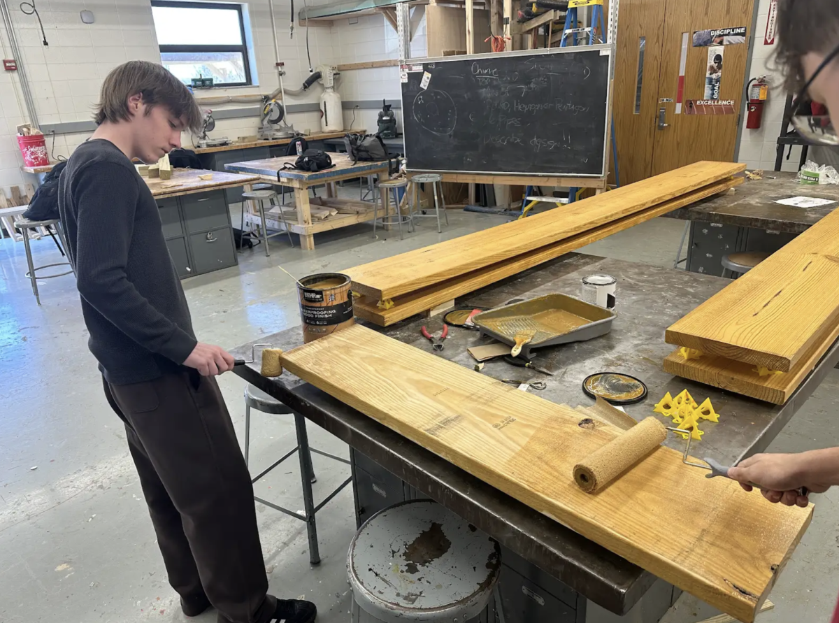 "Sealing wood in shop class, sophomore Drew Black works on crafting a standing flower bed. This week, Bryan Werner’s general carpentry class worked on making flower beds and gardens for Princes Lakes retirement home as an effort in bettering the community. “This kind of work is very important to me,” Black said. “In class we do good deeds and participate in volunteer work for our community.”