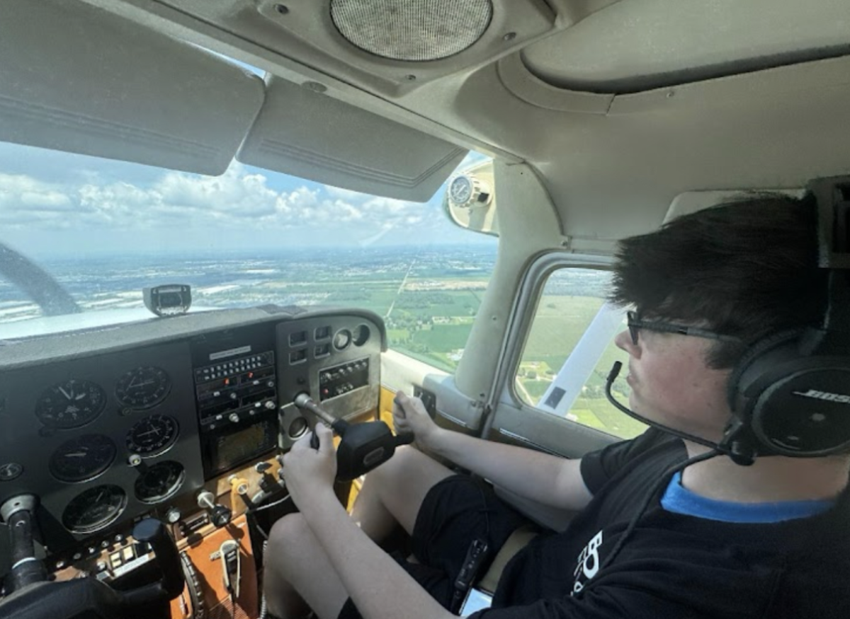 Senior Ty Black sits in the cockpit of a plane, maneuvering the controls in order to direct it towards the runway.