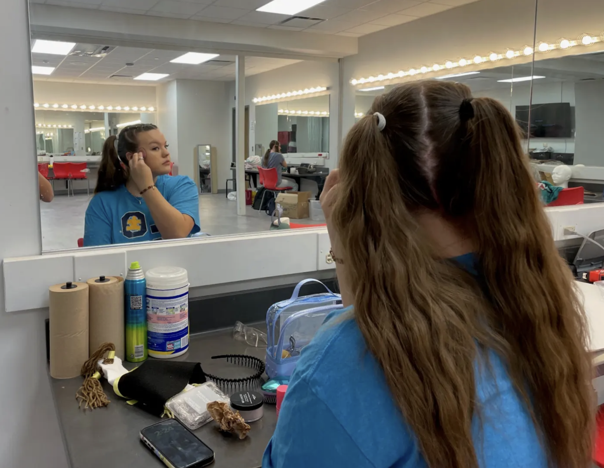 Senior Paige Gordon puts on makeup to rehearse for this years spring play, “Puffs.” Students in the play all do hair and makeup to help portray each of their characters. “Stage makeup is to help accent our face and make our features more noticeable,” Gordon said. “We mainly focus on darkening our eyes, highlighting our bone structure, and lighting up our face.”