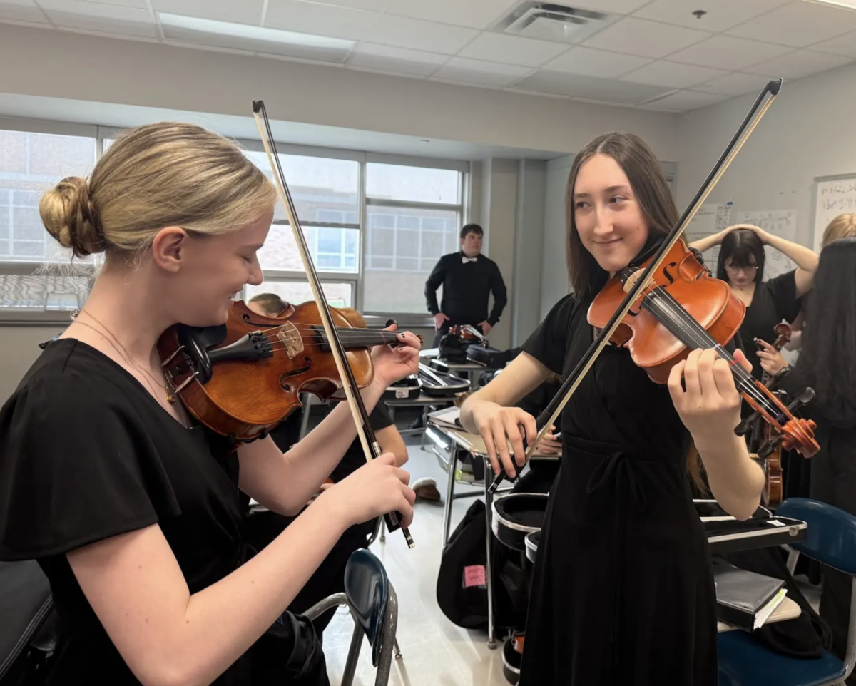 Preparing for their ISSMA competition sophomores Abigail Watson and Maya Kriech warm up their violins. Last weekend the concert orchestra participated in their ISSMA competition and received the highest award gold with distinction .”I really enjoyed ISSMA because we got to perform and show how hard we had been working” Kriech said. “It was fun seeing this orchestra grow from the moment we got are music to the moment we were playing it on stage.”